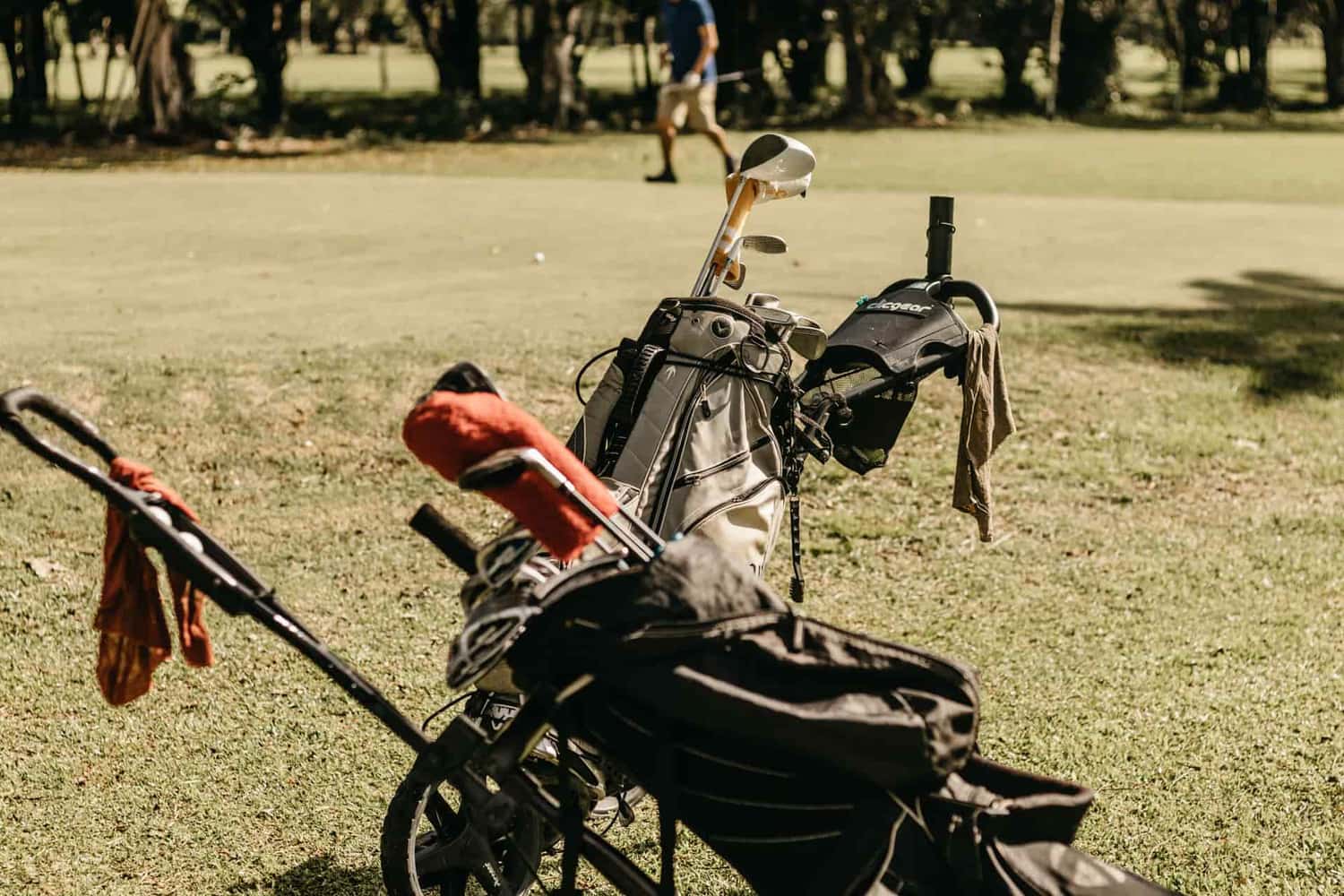 A golf stand bag full of clubs out on the course